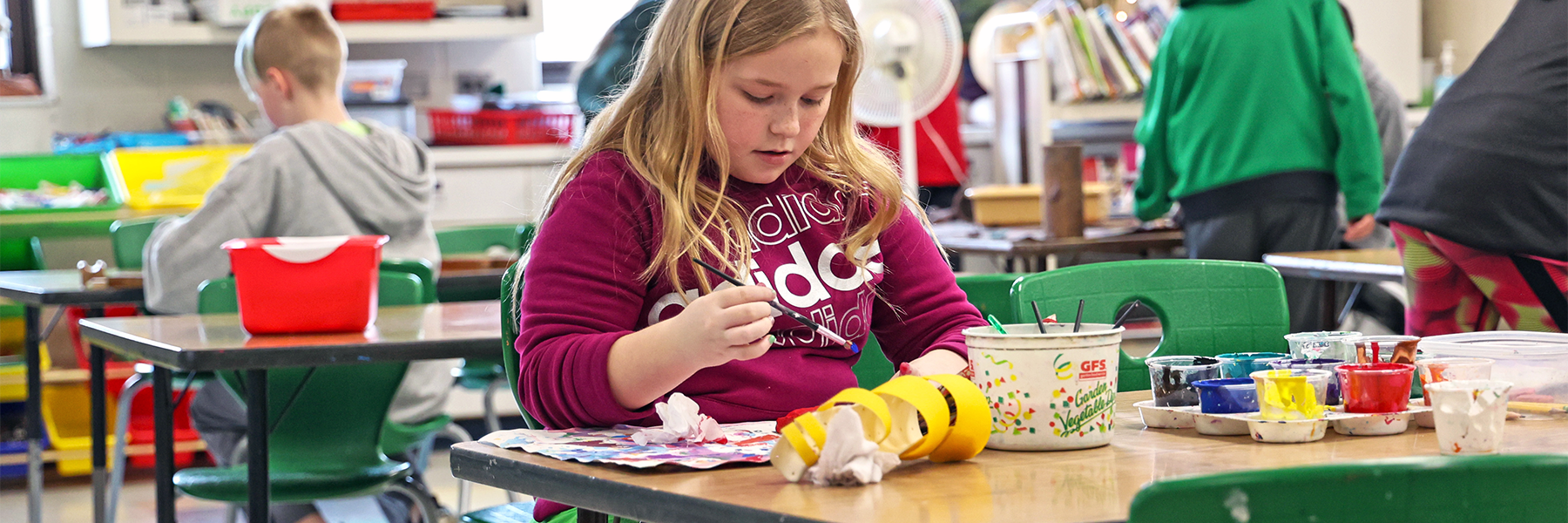 Girl in art class painting at desk