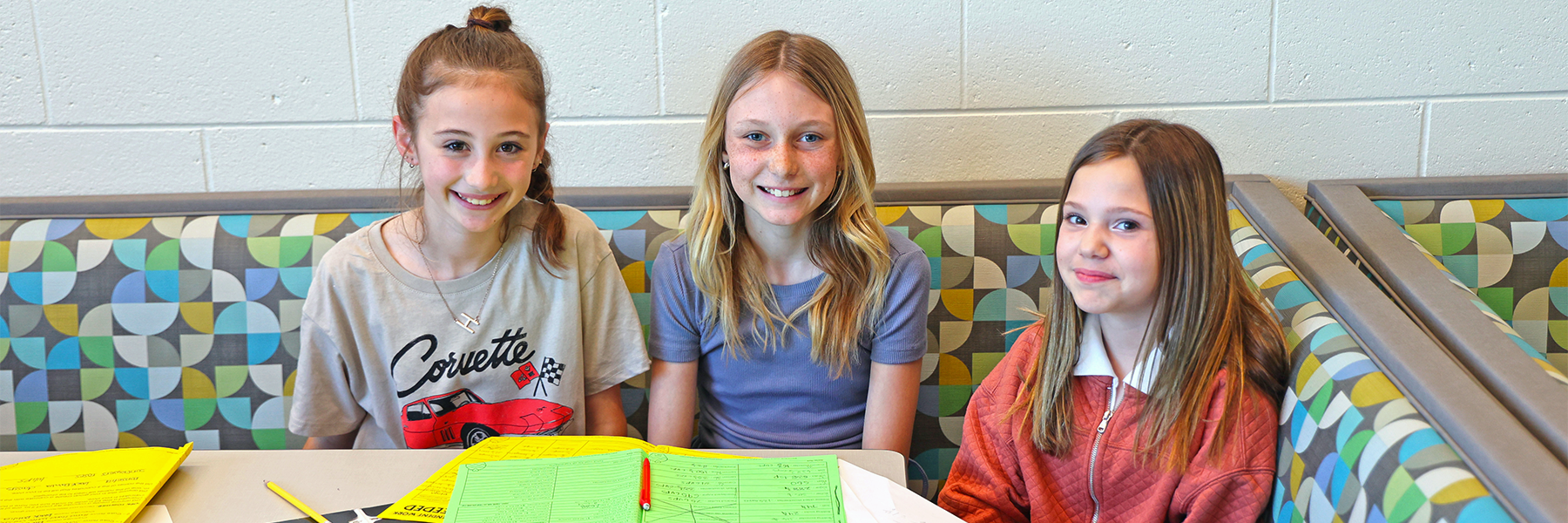 Three girls in booth working on schoolwork