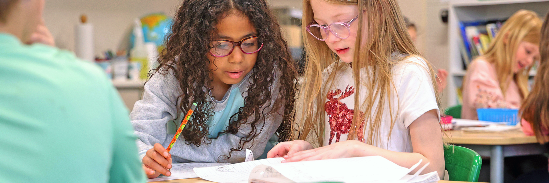 Two girls working together on classwork at desk