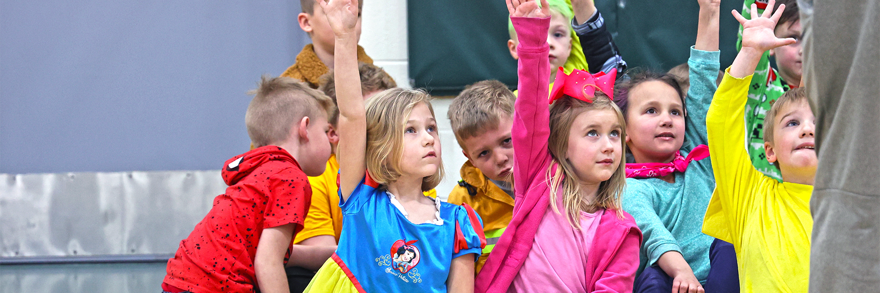 Kids raising hands wearing colorful character outfits