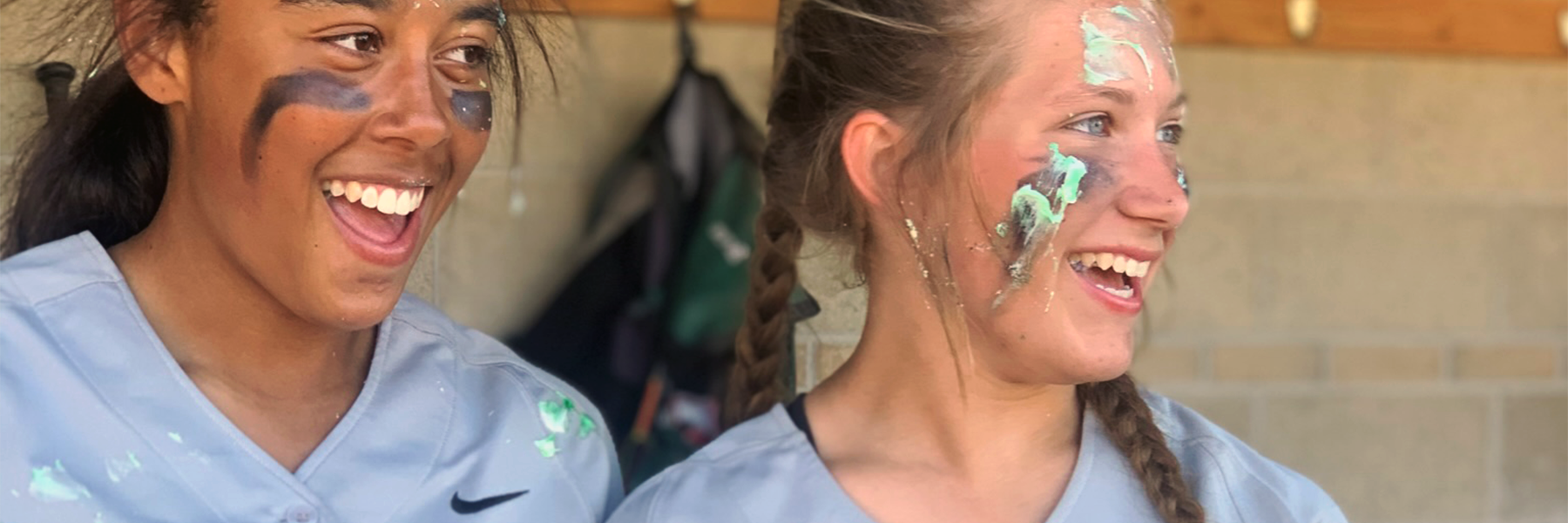 Two softball players laughing