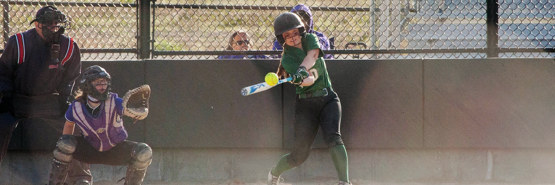 Softball player hitting ball in the dust