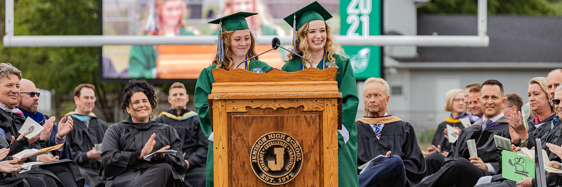 Two female students speaking at podium 