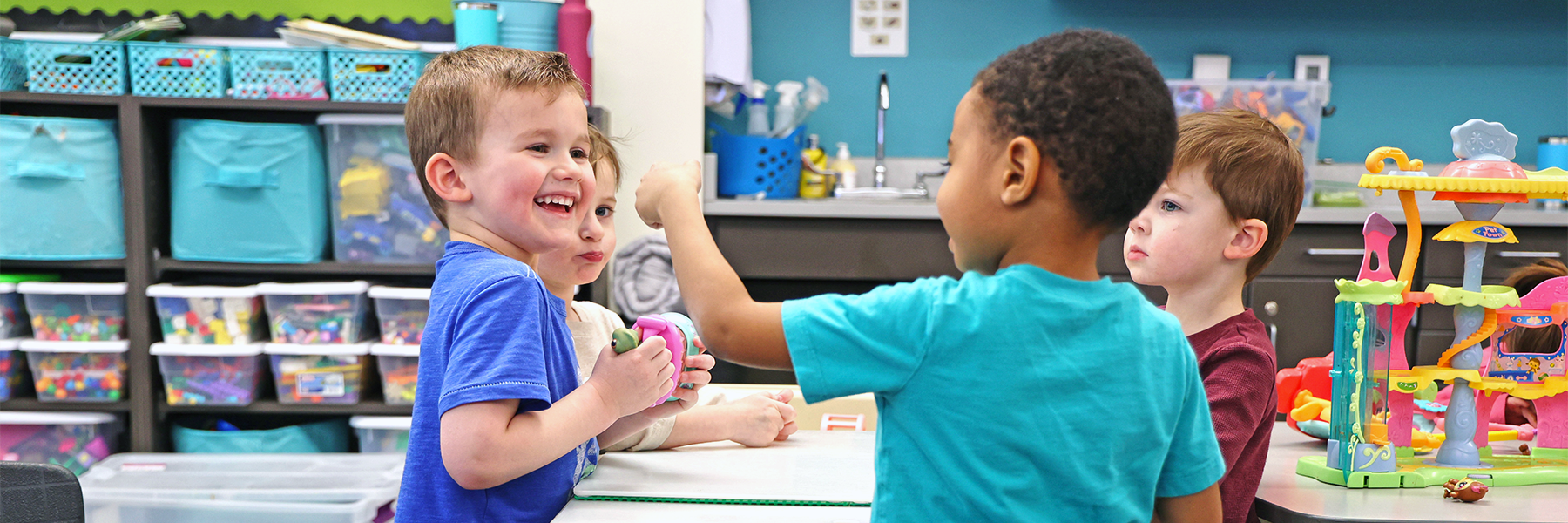 Kids laughing while active at table in classroom