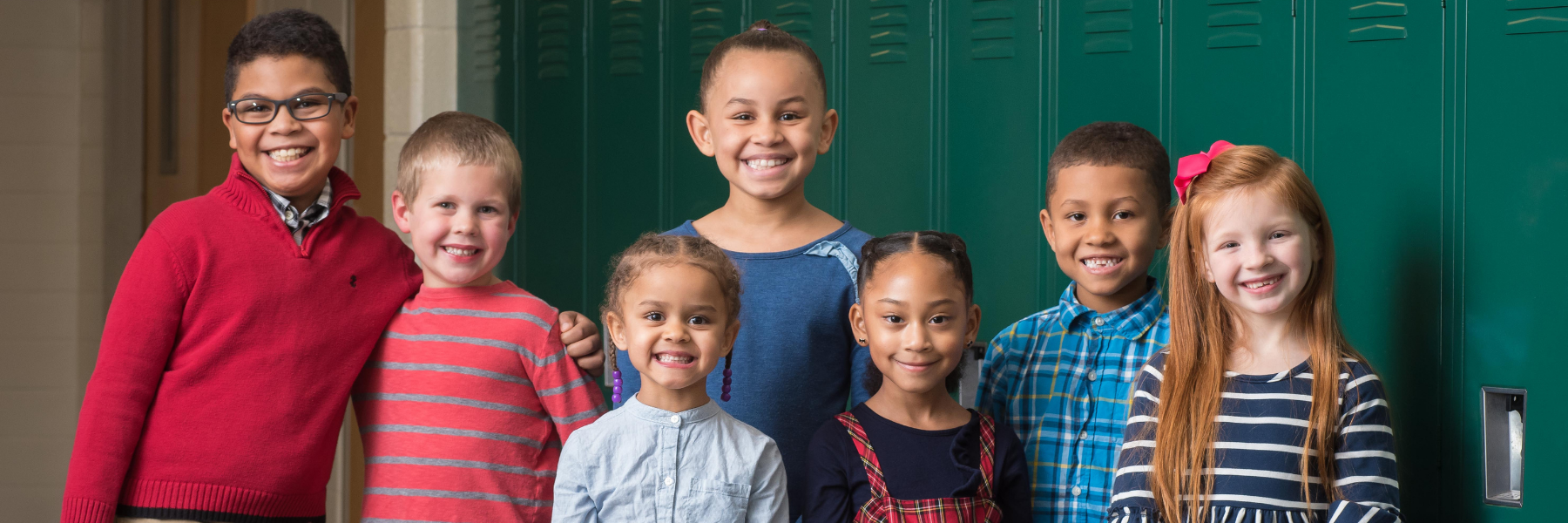 Students smile standing in front of lockers.